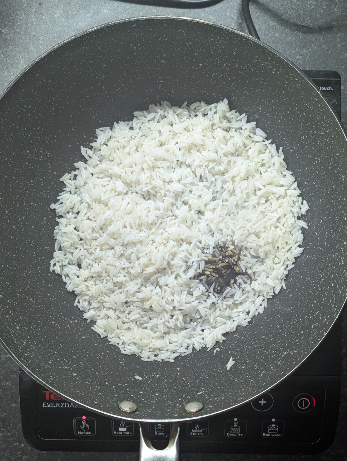 Cold leftover rice in a frying pan with soy sauce ready to be stir-fried for nasi goreng kampung.