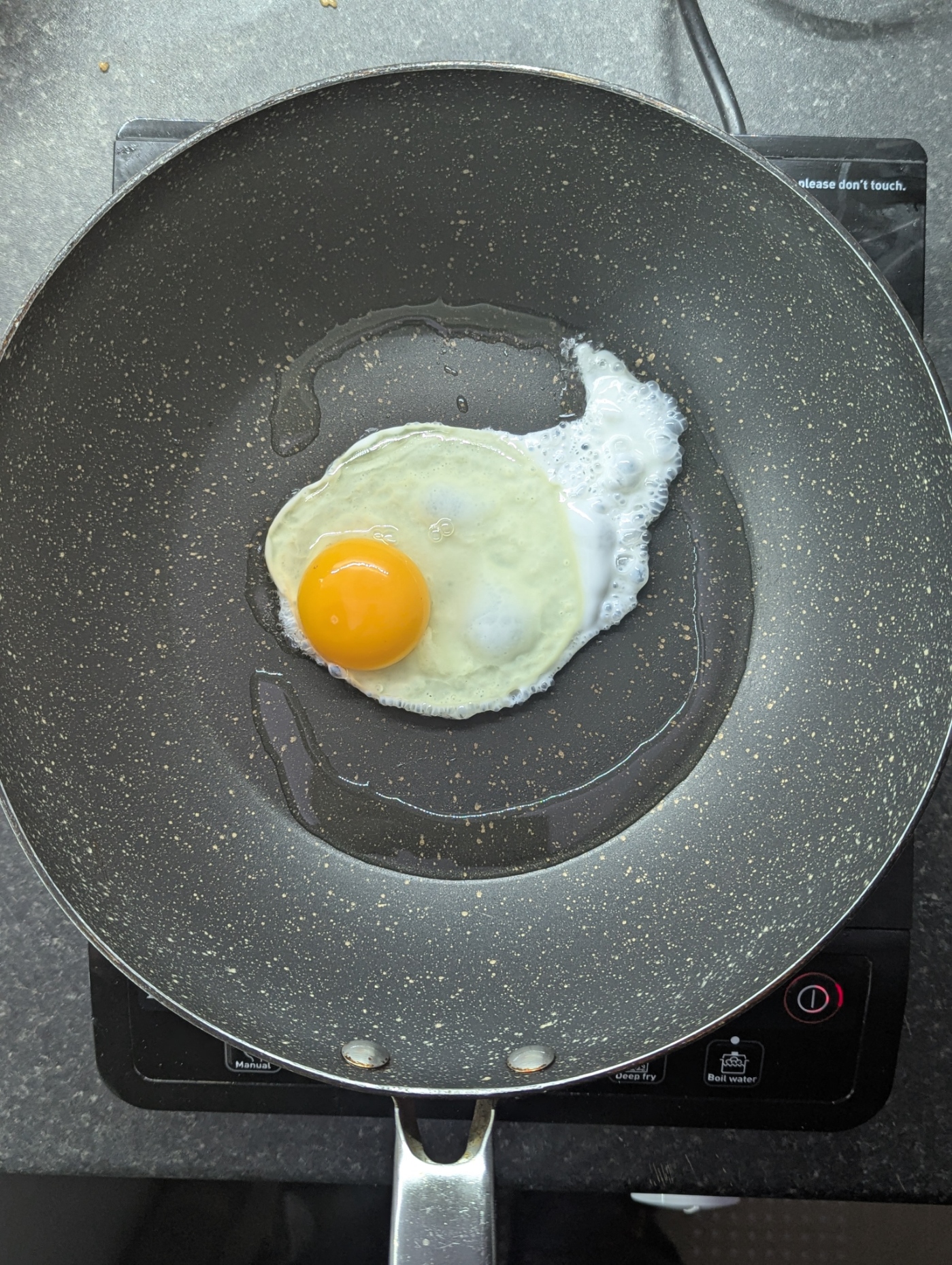 Crispy fried egg cooking in a pan, ready to top nasi goreng kampung.