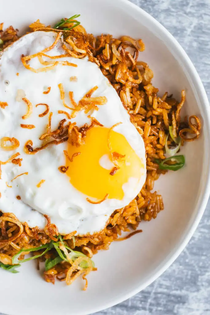 Close-up of nasi goreng kampung topped with a crispy fried egg and fried shallots.