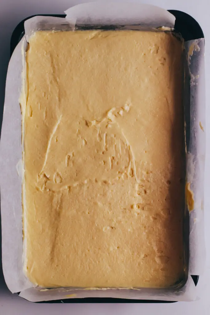 Vanilla traybake batter spread evenly in a lined rectangular baking tin.