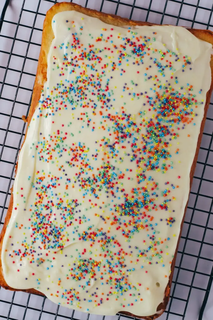 Vanilla traybake topped with smooth white icing and colourful sprinkles.